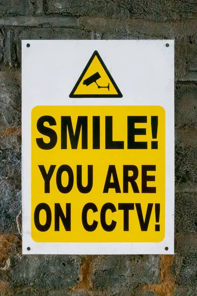 あなたがレンガの壁にCctvの看板にいる笑顔 — ストック写真