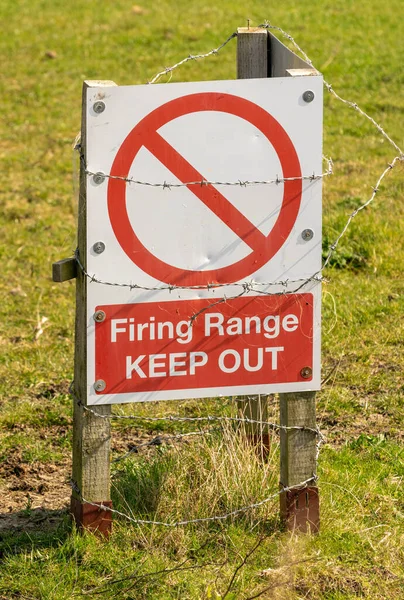 Firing range warning sign wrapped in barbed wire