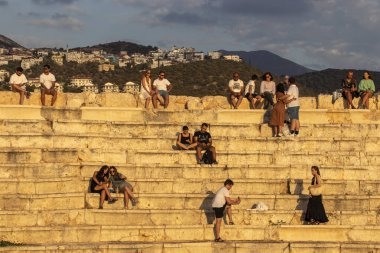 Kas, Türkiye - 14 Eylül 2021. Turistler antik tiyatronun merdivenlerinde oturur ve gün batımını izlerler..