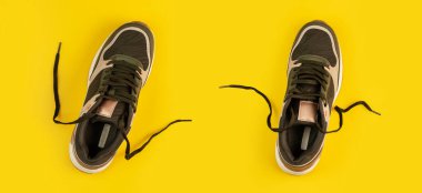 Sarı arka planda bir çift spor ayakkabısı. Bağcıkları çöz. Üst görünüm.