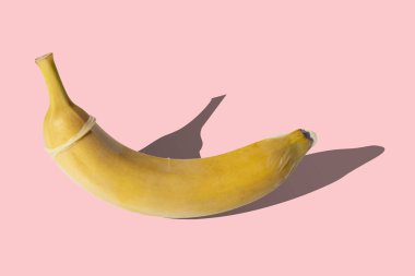 Mercan zemininde prezervatifli taze sarı muz. Cinsel yolla bulaşan enfeksiyon kavramı (STI).