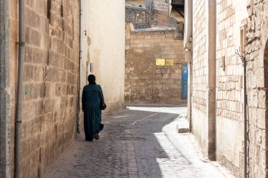 Urfa, Türkiye - 6 Eylül 2021. Geleneksel İslami giysiler içinde bir kadın boş sokakta yürüyor. Arka plan.