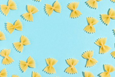 Mavi arka planda pişmemiş İtalyan farfalle makarnası. Kopyalama alanı olan üst görünüm.