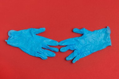 Kırmızı arka planda mavi lastik eldivenler.