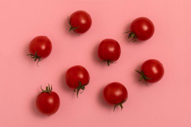Pembe arka planda kırmızı kiraz domatesleri. Üst görünüm.