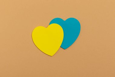 Paper yellow and blue hearts on a beige background. Top view.