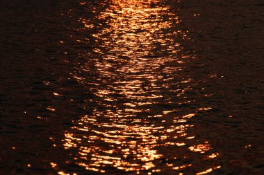 Deniz yüzeyindeki altın renkli ışık yolu. Kapat..