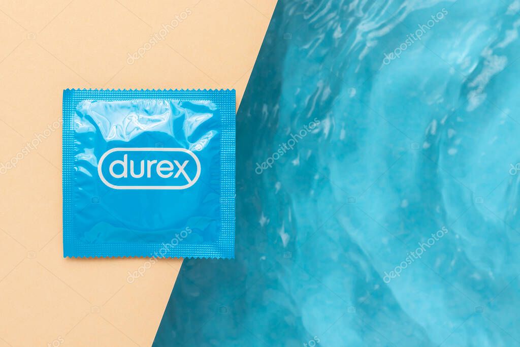 Lviv, Ukraine - June 19, 2022. Durex Condom on pastel yellow background next to the blue wavy water.