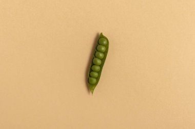 Bej arkaplanda yeşil bezelyeler. Üst görünüm.
