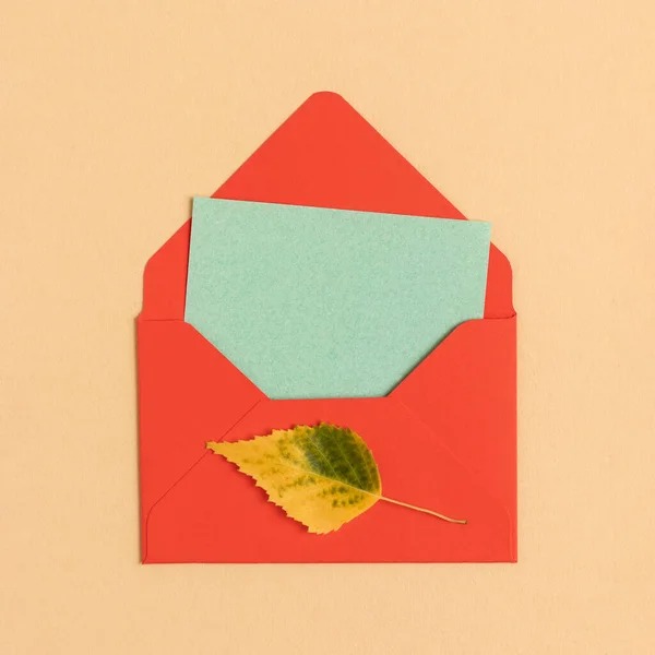 Red postal envelope with autumn yellow leaf and copy space.