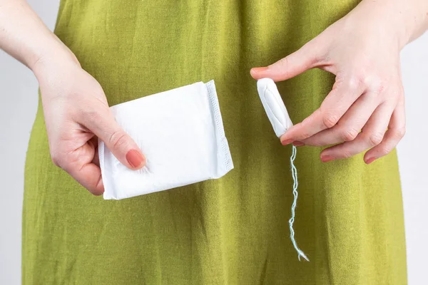 Kadının elinde tampon ve regl pedi var. Kapat..