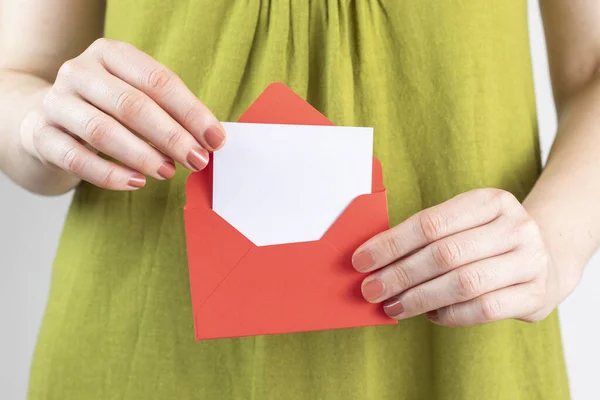 Woman holds red envelope with a greeting card in her hand. With copy space.