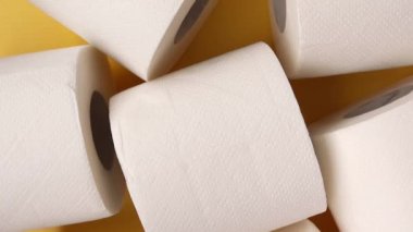 Rolls of white toilet paper on a yellow background. Top view. Rotate 360 degrees.