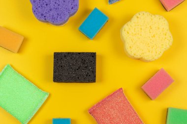 Soft multi-colored cleaning sponges on a yellow background. Flat lay.