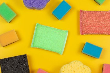 Soft colorful cleaning sponges on a yellow background. Flat lay.