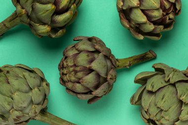 Big fresh artichokes on green background. Top view.