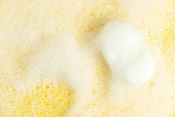 Bar soap and white foam on a yellow background.