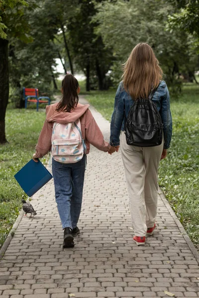 Mother walks her daughter to school. A walk in the park.