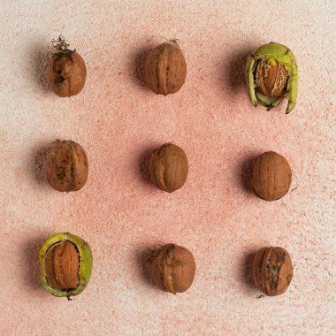 Yeşil kabuğun içinde ve dışında cevizler. Kırmızı arkaplanda, üst görünümde.