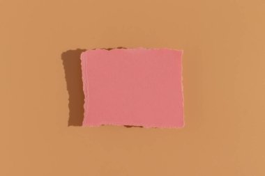 Bej arka planda pembe tebrik kartı. Sert ışık, üst görünüm.