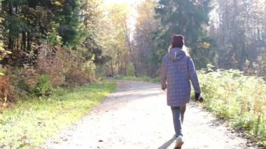 Kızların silueti arkada. Sonbahar parkında yürüyen bir kız..