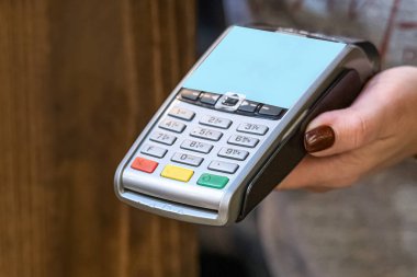 Ödeme için kredi kartı okumak için terminali olan bir kadının eli yakın plan..