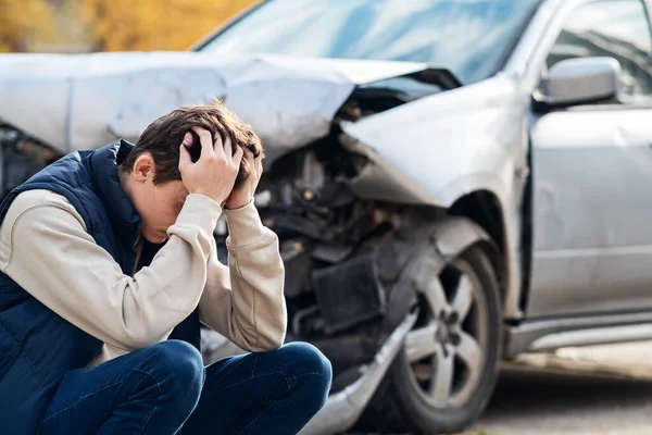 Un hombre frustrado cerca de un coche roto. Agarré mi cabeza al darme cuenta de que el daño es grave, el coche no tiene reparación.. — Foto de Stock