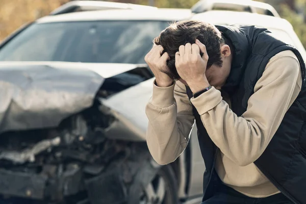 En frustrerad man nära en trasig bil. Tog mitt huvud inser skadan är allvarlig, bilen är bortom reparation. — Stockfoto
