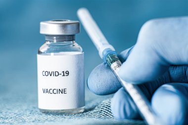 Bir doktor koruyucu mavi tıbbi eldivende bir ampul Sputnik V koronavirüs aşısı tutuyor.