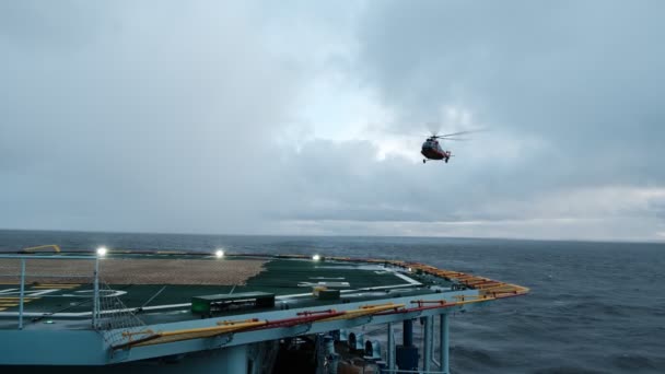 O helicóptero pousa no convés com um hover. Um voo de treinamento com um pouso de treinamento no heliporto de um navio em movimento. — Vídeo de Stock