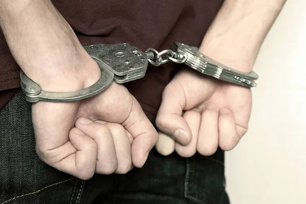 The criminal was detained by the police. The handcuffed hands clenched into fists. Stock Image