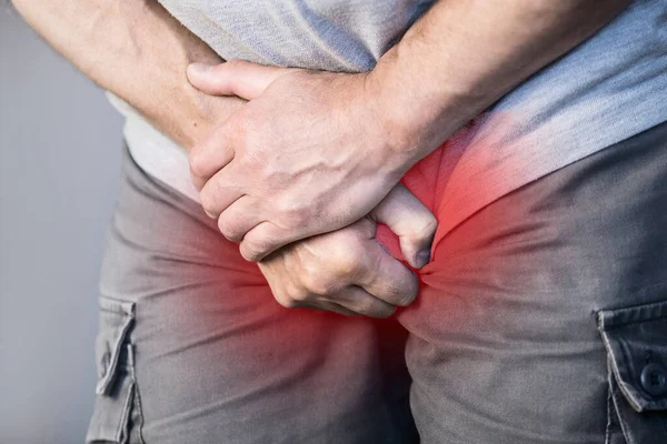 A view of a man from the front holding his crotch. Pain in the groin and bladder. The concept of pain in men as a result of prostatitis, inflammation of the bladder or genitourinary system. Frequent
