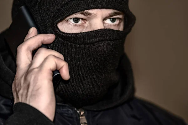 A criminal in a black balaclava and a hoodie in the dark. The concept of crime growth, robbery and fraud, unemployment and malice. — 스톡 사진