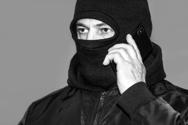 Black and white photo criminal in a black balaclava and a hoodie in the dark. The concept of crime growth, robbery and fraud, unemployment and malice. — 스톡 사진