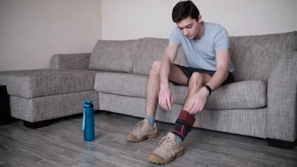 Il tizio mette una benda compressiva sul ginocchio ferito. Preparandosi alle attività sportive, il punto dolente è evidenziato in rosso.. — Video Stock