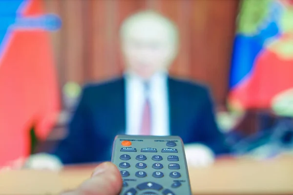 Enabling the live broadcast of the politicians appeal. An important political event. The remote control of the TV is in your hand, it is directed at the TV.