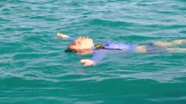 Bir adam elleri yanlara dönük olarak deniz suyunda yüzer. İş adamı gömlek, kravat, çorap ve iç çamaşırı giyer. Özgürlük ve zevk kavramı. Yavaş çekim, 4k