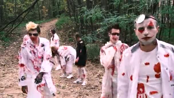 Halloween. Zombies kijken overdag door het bos naar de camera. Dode mannen in witte kleren bevlekt met bloed, 4k. — Stockvideo