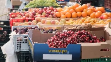 Sağlıklı yiyecekler. Plastik ve ahşap kutularda duran taze böğürtlen ve meyvelerin yan görüntüsü. Güneşli bir günde doğal organik tarım ürünlerinin sebze ve meyve pazarı. Arnavutluk, Durres, 23 Temmuz 2021