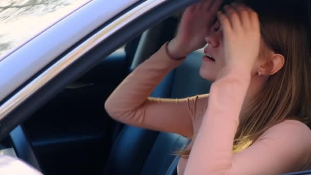Una vista laterale attraverso il finestrino di una donna seduta al volante. La stanca frustrata si aggrappa alla testa e sospira pesantemente. Rallentatore, 4k — Video Stock
