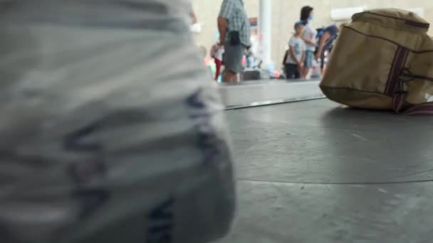 Bagageband op het vliegveld. Bagage claim. Onderaanzicht. De mensen op de achtergrond wachten op hun bagage. 4k, slow motion. Tirana, Albanië, 23 juli 2021 — Stockvideo