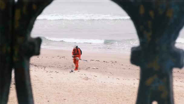 L'homme marche avec un détecteur de métaux dans le sable. Détecteur de métaux électronique et une pelle. Un homme cherche le luxe perdu par les touristes dans l'eau et sur la plage. Bord de mer, vagues mousseuses. 4k, au ralenti — Video