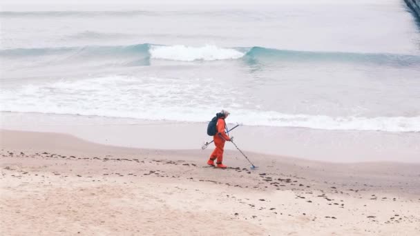 Muž hledá ztracený luxus s elektronickým detektorem kovu na pláži za oblačného podzimního dne. Zpomalený pohyb, 4k — Stock video