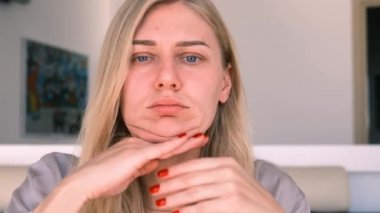 Yüz geliştirme. Çift çene problemi. Çekici sarışın bir kadının portresi parmaklarıyla yüz masajı yapıyor. Kişisel bakım. Yaşla ilgili değişikliklerle savaşmak. 4k, ağır çekim.