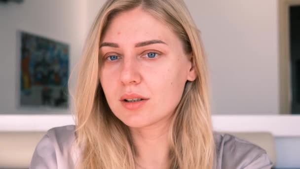 Jovem mulher loira sedutora com olhos azuis olha pacificamente para a câmera, 4k, câmera lenta — Vídeo de Stock