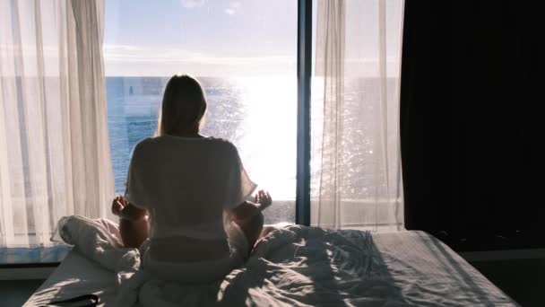 精神衛生だ。海とパノラマの窓を背景に瞑想の若い女性のリアビュー。タイムラプス4k — ストック動画