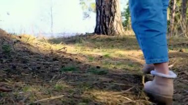 Kadın ayağı botlarla ormanda yürüyor, yapraklara ve tümseklere basıyor, gerçek zamanlı, 4K, yakın plan.