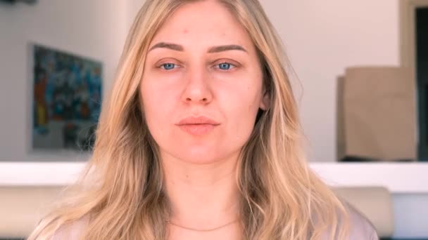 Selbstbewusste junge, schöne, blauäugige Blondine ohne Make-up blickt in die Kamera. Morgenporträt eines Mädchens. Zeitlupe, 4k — Stockvideo