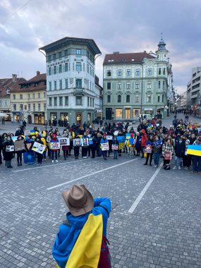 Ukrayna 'daki savaşı protesto etmek. Meydanda bayrakları ve posterleri olan bir sürü insan savaşı durdurup barış için slogan atmayı durdurdu. Ukraynalıların barışçıl mitingi. Slovenya, Ljubljana, 28.02.2022