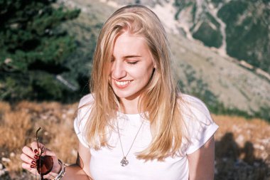 Güneşli bir günde, kendine güvenen, gülümseyen, gülümseyen sarışın kadının portresi. Mutlu kız gülümsüyor.